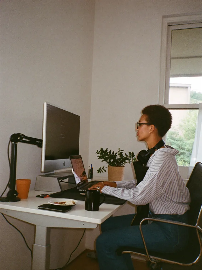Diseñadora trabajando con notebook en soporte y monitor